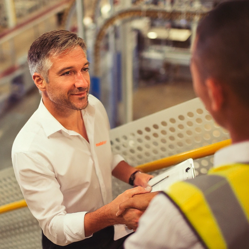 Profissional da Madater cumprimentando colaborador em ambiente industrial.