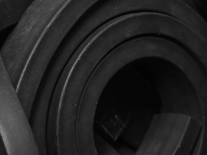 Rolos de borracha preta em detalhe, evidenciando a textura e a densidade do material utilizado em soluções técnicas da Madater.